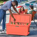 A man putting a bottle and a can in a CaterGator outdoor cooler.