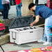 A person opening a CaterGator outdoor cooler filled with beer bottles.