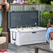 A couple sitting on a patio with a CaterGator outdoor cooler on the table full of bottles of beer.