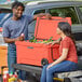 A man and woman sitting on the back of a truck with a CaterGator cooler.