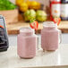 Two mason jars filled with pink Live Pure Strawberry Acai smoothies on a counter.