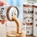 A hand pours La Colombe Mocha Draft Latte into a glass.