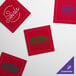 A group of red square Choice single-use cotton napkins with four different logos on them.