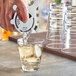 A person pouring a drink into an Acopa Endure stackable rocks glass filled with ice.