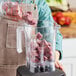 A person pouring Live Pure Acai Tropical Boost smoothie cubes into a blender.