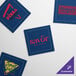 A navy blue square beverage napkin with a yellow triangle and green text.