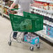 A man in a grey shirt pushing a green Regency shopping cart.