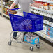 A man pushing a Regency blue plastic grocery cart in a grocery store aisle.