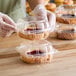 A person in gloves putting a pastry in a Choice clear hinged plastic container.