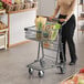 A woman pushing a Regency Supermarket shopping cart in a grocery store aisle.