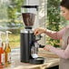 A woman using a Mahlkonig E65W GBS espresso grinder.