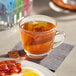 A plate of bacon and eggs and a cup of Lipton Peach Mango black tea on a table.