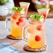 Two glass mugs of Tazo watermelon and cucumber drink with fruit on top.