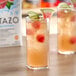 A glass of Tazo watermelon cucumber juice with ice and a slice of watermelon.
