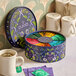A round box of Pukka Organic Workday Wellness Tea with colorful tea bags on a table next to a cup of tea.