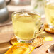 A glass cup of Pukka Organic Lemon, Ginger, and Manuka Honey tea with a tea bag in it.