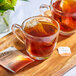 A wooden tray with two glass cups of Tazo Pumpkin Spice Chai tea with tea bags.