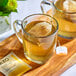A wooden tray with two glass mugs of Tazo Glazed Lemon Loaf tea with a tea bag in one mug.