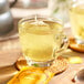 A glass cup of Pukka Organic Lemon, Ginger, and Manuka Honey tea with a tea bag in it.