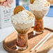A glass of iced gingerbread spice latte topped with whipped cream and a cookie, served on a wooden tray.