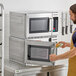 A man in an apron using a Solwave commercial microwave to heat a plate of food.