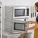 A man in an apron opening a plate of food in a Solwave commercial microwave.