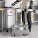 A man in gloves and an apron standing in a professional kitchen next to a MirOil fryer oil filter machine.