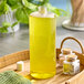 A Captiva Containers clear plastic cylinder bottle filled with yellow liquid on a tray.