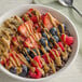 A bowl of fruit with a spoon and Producers Peanut Company Natural Creamy Peanut Butter.