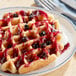 A plate of waffles with Wyman's wild blueberries and syrup on top.