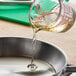 LouAna Southern Fry Soybean and Peanut Oil Blend being poured from a measuring cup into a pan on a kitchen counter.