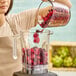 A woman pouring Wyman's mixed berries into a blender.