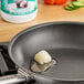 A frying pan with a piece of garlic frying in LouAna Organic Coconut Oil.