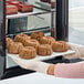 A person holding a tray of White Toque gluten-free vegan molten banana cakes.