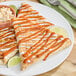 Two tortillas on a plate with Valentina Red Label Mexican Hot Sauce.