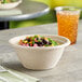 A World Centric compostable take-out bowl filled with food on a table.