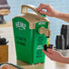 A hand pouring Heinz Sweet Relish from a green and tan Heinz countertop pump dispenser.
