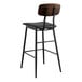 A black bar stool with a black vinyl seat and wood backrest.