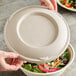 A person holding a World Centric compostable fiber bowl with a World Centric compostable fiber lid over a salad.