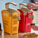 A person using a Heinz ketchup dispenser to pour ketchup over a paper bag of food.