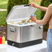 A woman putting cans of soda in a Choice stainless steel beverage cooler.