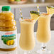 Two glasses of Dr. Smoothie Classic Pineapple Blend next to a bottle of pineapple juice.