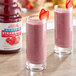 Two glasses of pink Dr. Smoothie Classic Strawberry smoothie with strawberries on top.
