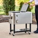 A woman opening a Choice stainless steel beverage cooler cart.