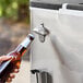 A hand using a bottle opener on a stainless steel beverage cart.