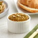 A small white ramekin of Vor Pure Pistachio Butter on a table with a croissant.