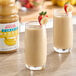 Two glasses of banana smoothie with strawberries on a white background.