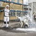 A man using a Karcher upright hot water pressure washer to spray concrete.