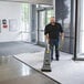 A man using a Karcher Sensor XP 18 upright vacuum cleaner to clean a carpet.