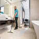 A man using a Karcher commercial steam cleaner to clean a bathroom floor.